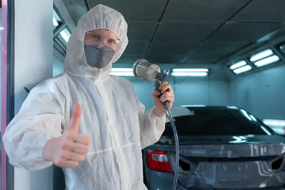 auto-mechanic-in-car-spray-room-use-a-spray-nozzle ویژگیهای بهترین مراکز صافکاری و نقاشی خودرو در ریچموند هیل