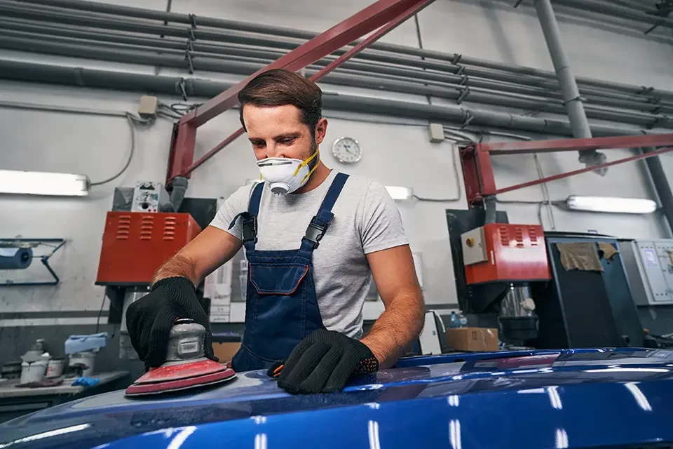 man-in-car-repair-shop-sanding-automobile-with-too The Process of "Scratch and Dent Car Repair Near Me"