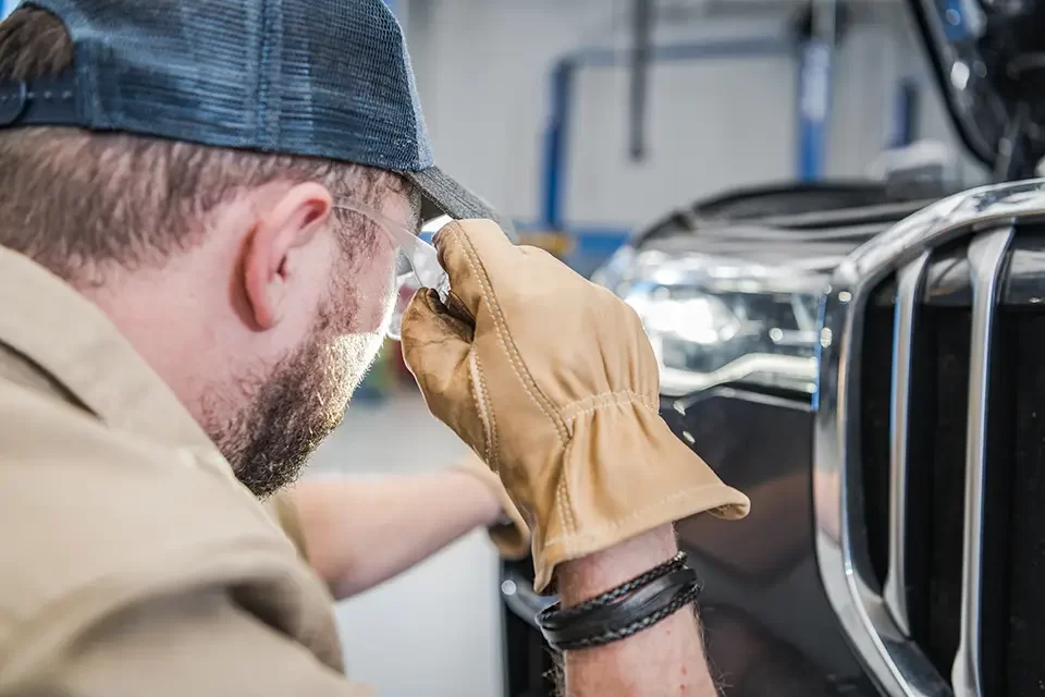 mechanic-checking-car-headlights مراحل آموزش صافکاری ماشین