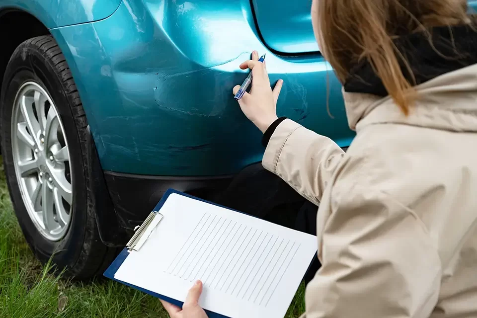 person-inspecting-car-bumper-damage-with-clipboard How Auto Stars Collision & Mechanic Works with Definity Insurance