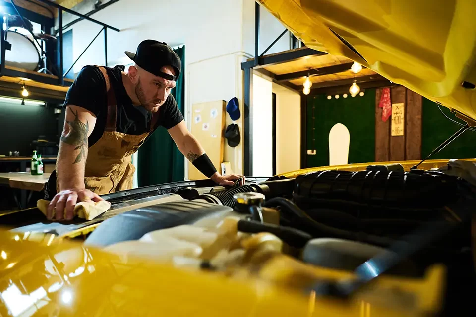 young-serious-man-in-apron-and-baseball-cap-bendin Signs You Need to Visit Exhaust and Muffler Shops Near You